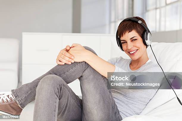 Photo libre de droit de Jeune Femme Assise Sur Une Chaise Avec Casque Souriant banque d'images et plus d'images libres de droit de Adulte