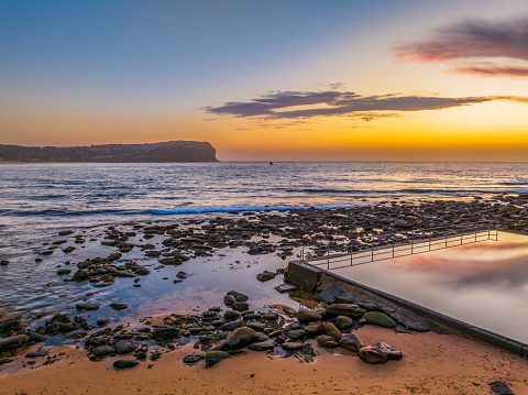 Pretty aerial sunrise with high cloud, seapool and small waves at  Macmasters Beach on the Central Coast, NSW, Australia.