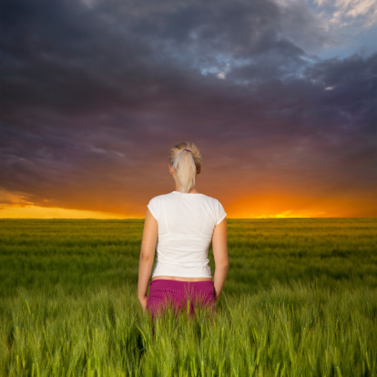 Young woman watching the sunrise in rye field