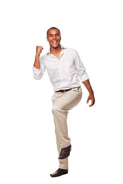 Handsome Businessman Celebrating. Isolated Handsome businessman smiling and standing with a knee lifted and a clenched fist in celebration. Vertical shot. Isolated on white. rolled up sleeves stock pictures, royalty-free photos & images