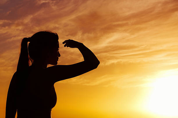 istock Silhouetted woman shielding eyes at sunset 182781997