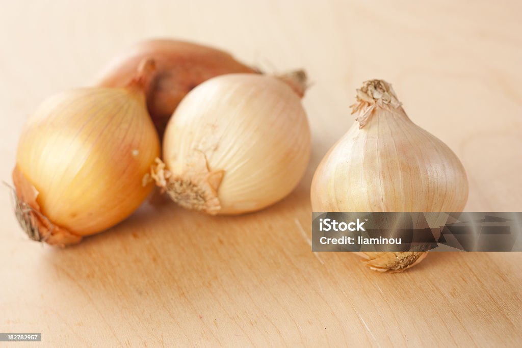 onions white unpeeled onion on wooden table with tree onions in the background Color Image Stock Photo