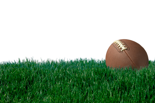 Football laying in Lush Grass against a white background.