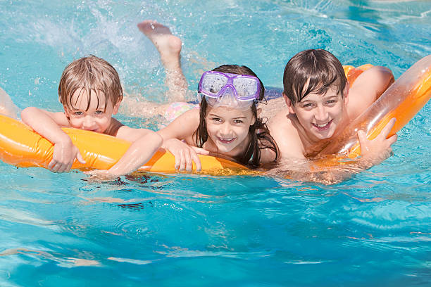 istock Three Children Playing on a Float in the Swimming Pool 182783884