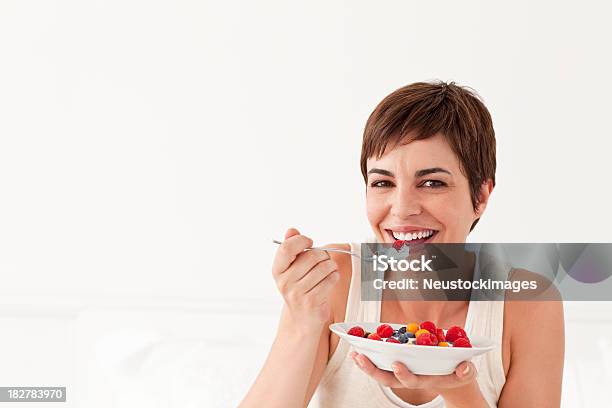 Foto de Jovem Mulher Sorridente Comendo Uma Tigela De Frutas e mais fotos de stock de Iogurte