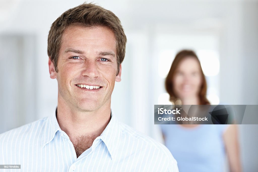 Sorridente bell'uomo con donna in sottofondo - Foto stock royalty-free di 30-34 anni