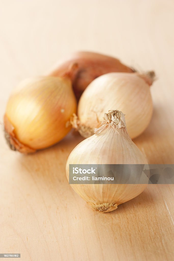 white onion unpeeled white onion on wooden desk with three onions in the background Color Image Stock Photo