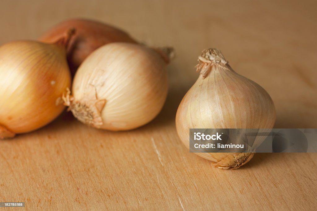 onion white unpeeled onion on wooden table with tree onions in the background Color Image Stock Photo