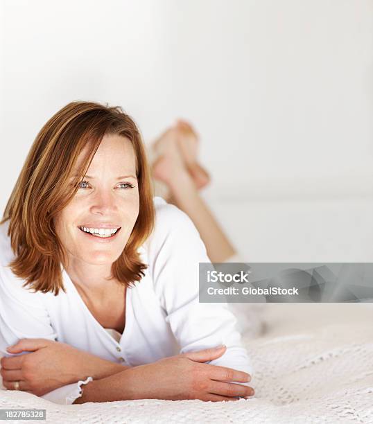 Uśmiech Dorosły W Średnim Wieku Kobieta Leżąc Na Łóżku W Domu - zdjęcia stockowe i więcej obrazów 30-34 lata