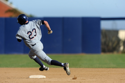 Slide, baseball action and athlete in a dirt for game or sports competition on pitch in stadium. Person, ground and  tournament performance by athlete or base runner in training, exercise or workout