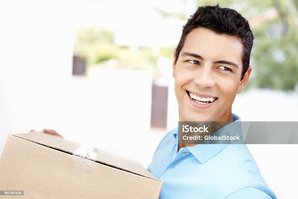 Счастливый человек с коробки в новый дом улыбается движущихся - Стоковые фото 20-29 лет роялти-фри