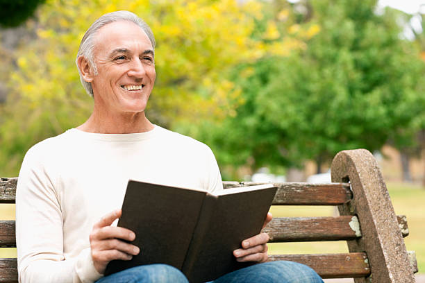 istock Senior Man Sitting On Park Bench With Book 182788587