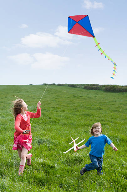 istock Two children flying a kite and model plane 182789123