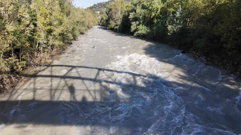 The Serio river swollen after heavy rainfall and floodwater crashing through valley. The water flows fast from the high valley to the plain. River in Province of Bergamo, northern Italy