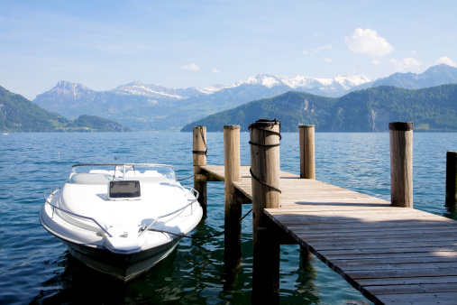 Boat roped up on a pole on Lake Lucerne with the Alps in the background.