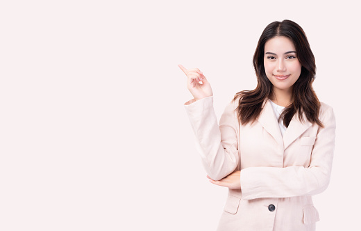 Young Asian business woman pointing up to copy space and looking at camera with smile face and happy Pretty girl act like a satisfied product, use for advertising with isolated on white background
