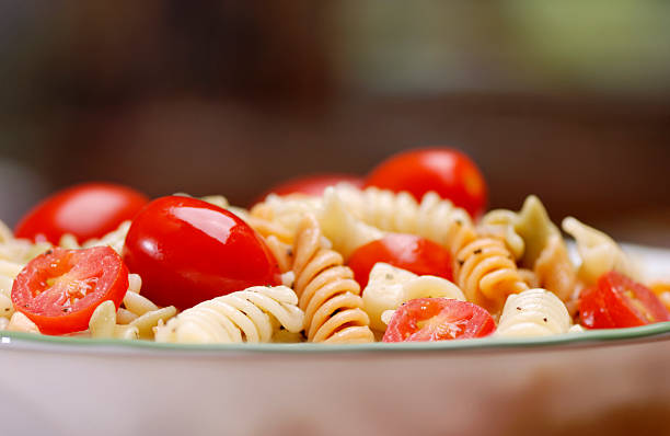 pasta salad with tomatoes and cheese in a bowl