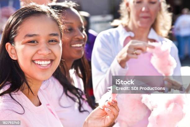 Foto de Jovem Mulher Comendo Cotton Candy Na Conscientização Do Câncer De Caminhada e mais fotos de stock de Adulto