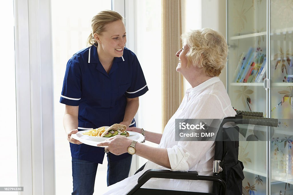 Infirmière donnant repas pour femme âgée en fauteuil roulant - Photo de Troisième âge libre de droits