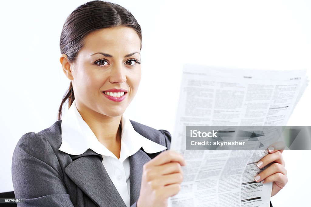 Business woman holding newspaper, looking at camera. "Attractive young businesswoman holding newspaper, looking at camera." Adult Stock Photo