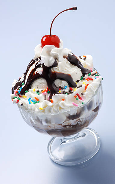 Ice cream sundae with cherry on top An ice cream sundae on a pastel blue background. rainbow sprinkles ice cream stock pictures, royalty-free photos & images