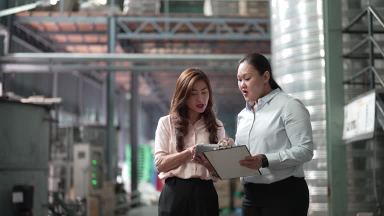 2 asian chinese female factory management and foreperson discussion in warehouse on goods delivery logistic and production schedule