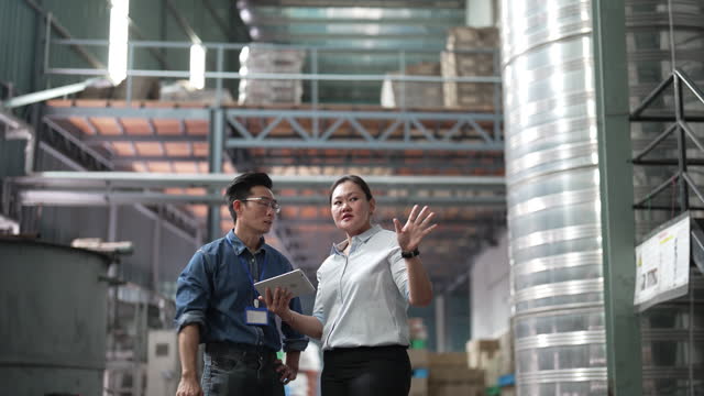 Asian female manager talking to warehouse foreperson worker in factory