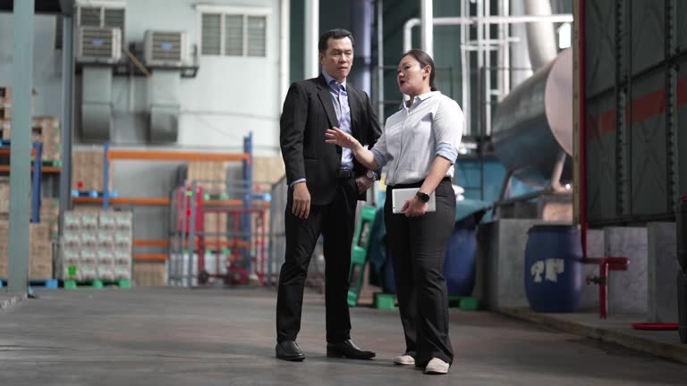 Asian businessman visiting factory listening to foreperson warehouse factory worker planning logistics shipping, quality control or export import goods