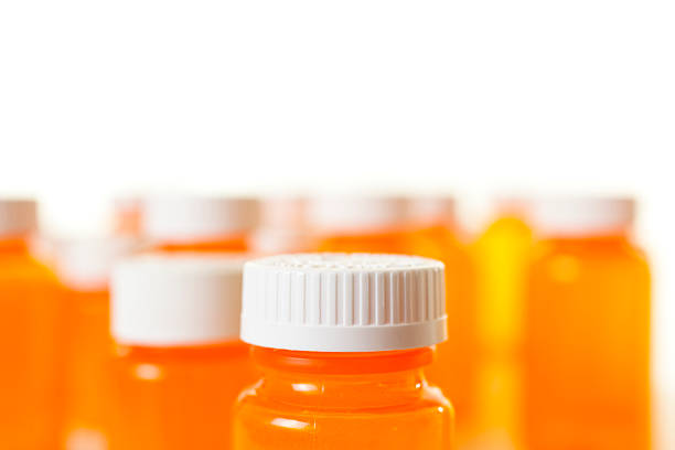 Collection of orange, prescription medicine bottles, all with lids.  Selective focus. White background. Nobody, empty.