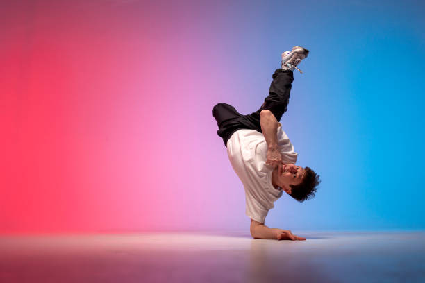 istock dancer doing acrobatic trick and dancing breakdance in neon red and blue lighting, young guy stands on his hands 1827955203