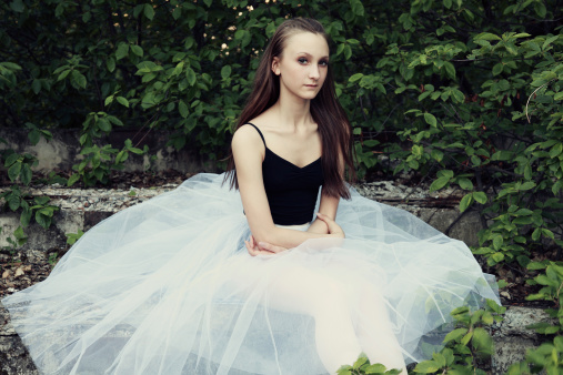 Sitting professional ballerina in chopin tutu on old steps.
