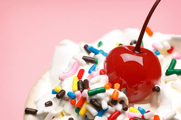 Cherry On Top A cherry on top of whipped cream and rainbow sprinkles. whipped food photos stock pictures, royalty-free photos & images