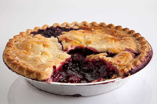 Boysenberry Pie "A fresh baked boysenberry pie with slice missing, on a deliberate gray background with natural reflection." marionberry stock pictures, royalty-free photos & images