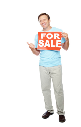 Happy mature man with for sale placard pointing at copy space against white background