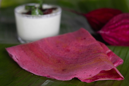 Beetroot ghee roast. A colorful, flavorful South Indian Crispy crapes made with fermented batter of rice and lentils mixed with beetroot. Served on banana leaf along with coconut green chilly chutney
