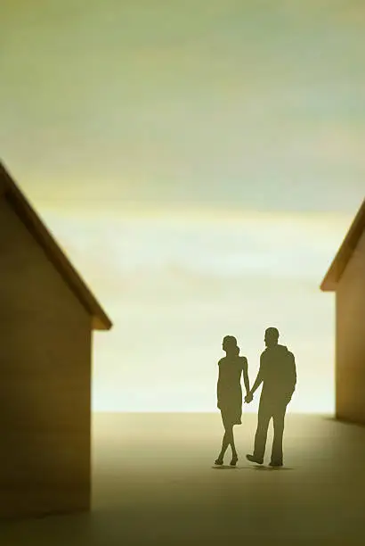 Silhouette couple walking among houses.This is a unique and original hand cut paper silhouette with accessories carefully crafted and owned by the photographer.