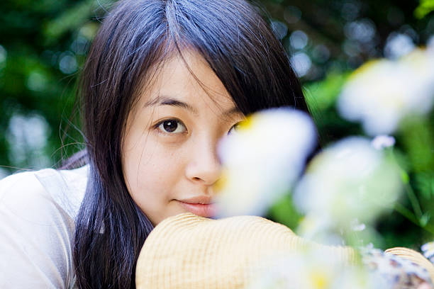 An asian girl is hiding behind the flowers.