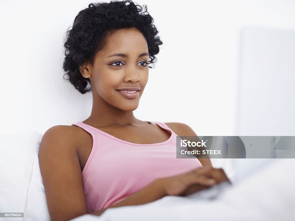 Uśmiechający się kobieta za pomocą laptopa w łóżku - Zbiór zdjęć royalty-free (20-24 lata)