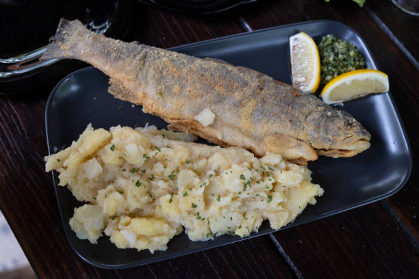 Fried trout fish, served alongside mashed potatoes and a small fresh salad