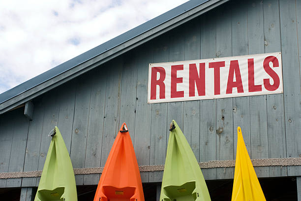 Brightly colored kayaks stand against a wall advertising rentals.see related: