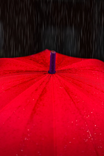 Detail of red umbrella as raindrops fall on the city