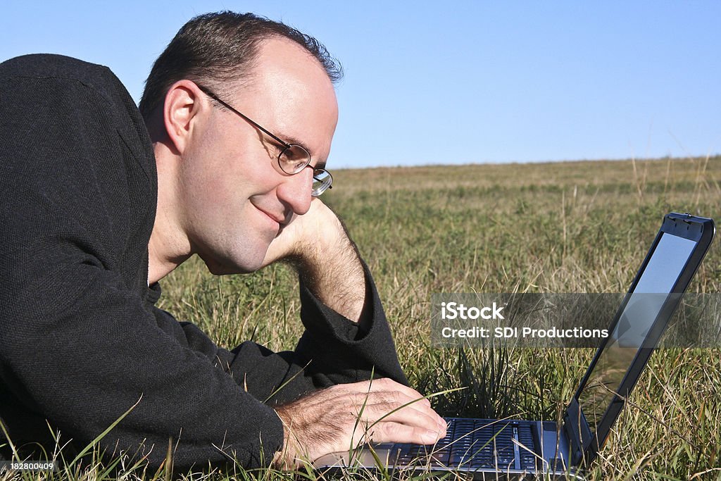 Hombre adulto usando ordenador portátil al aire libre en el césped - Foto de stock de Accesibilidad libre de derechos