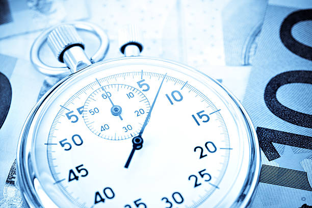 stopwatch on pile of euro banknotes can be used for various concepts - closeup