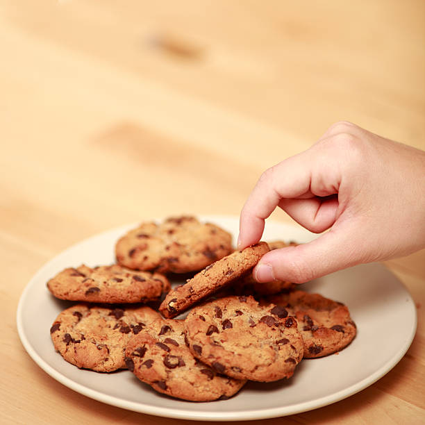 istock Hand picking a chocolate cookie from dish full of cookies. 182800703