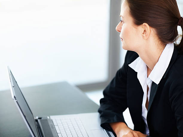 istock Business woman sitting with a laptop looking at copyspace 182800808