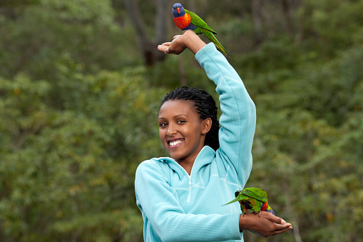 Attractive woman shows colorful parrots on her hands.