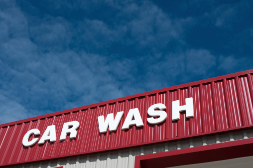 A car wash building sign with sky in background.