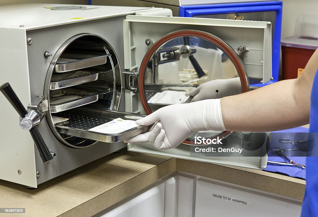 Tecnico Inserisce strumenti chirurgici per la sterilizzazione in Autoclave. - Foto stock royalty-free di Autoclave