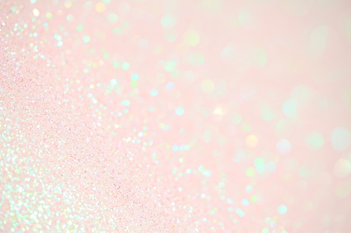 XXXL photo of very light pink iridescent sparkle glitter with selective focus on a diagonal to create mostly blurred sparkles of light in pastel greens and pinks.