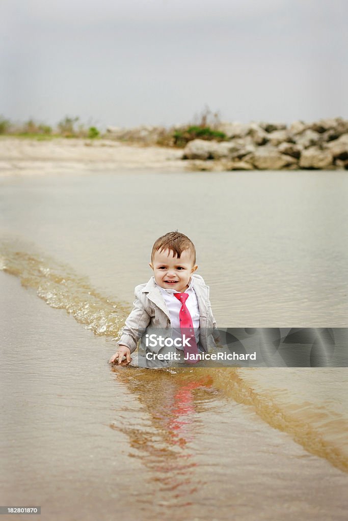 Little Businessman in Water Young child sitting in the water dressed in a business suit. 12-17 Months Stock Photo